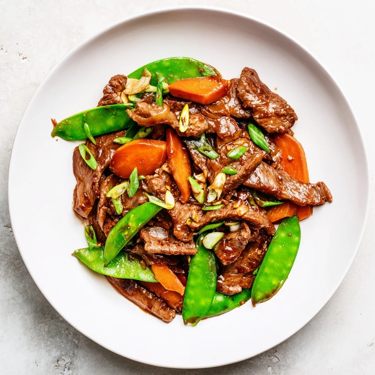 Beef Stir Fry with Snow Peas and Carrots glazed with savory sauce in a wok, ready to serve.