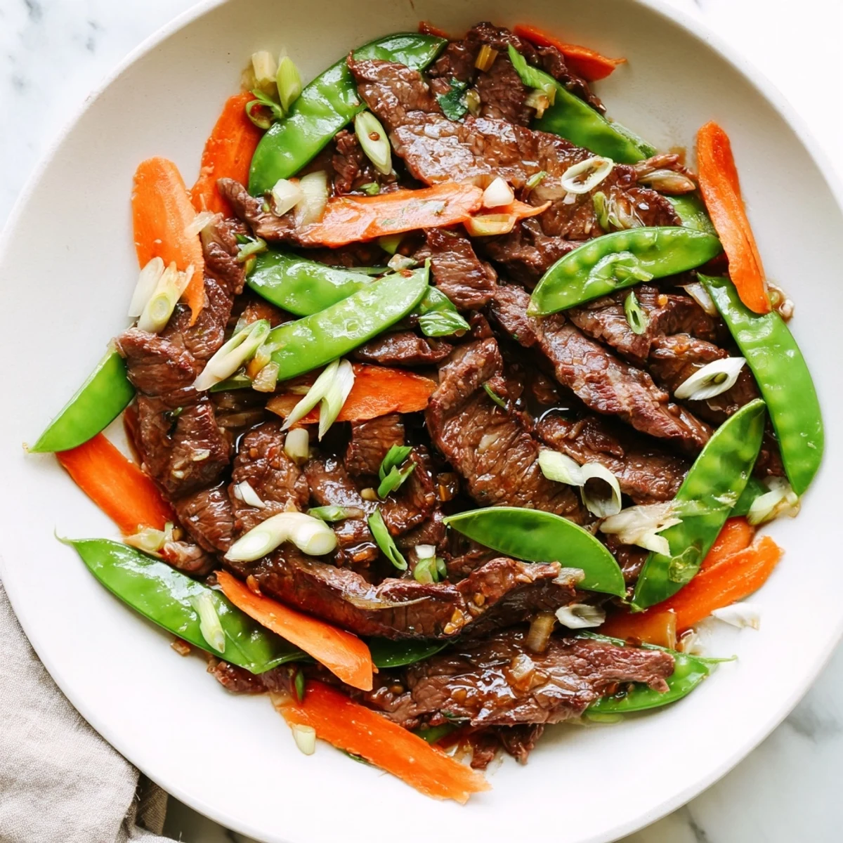 Beef Stir Fry with Snow Peas and Carrots plated with rice and chopsticks for a quick weeknight meal.