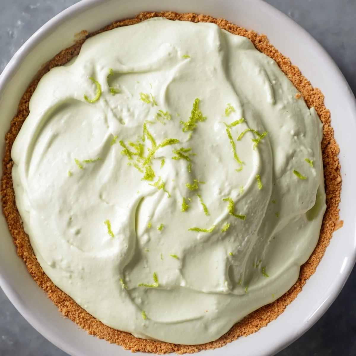 Tangy Key Lime Pie with Whipped Cream Topping features a crackly graham cracker base and a cloud of sweet vanilla whipped cream.