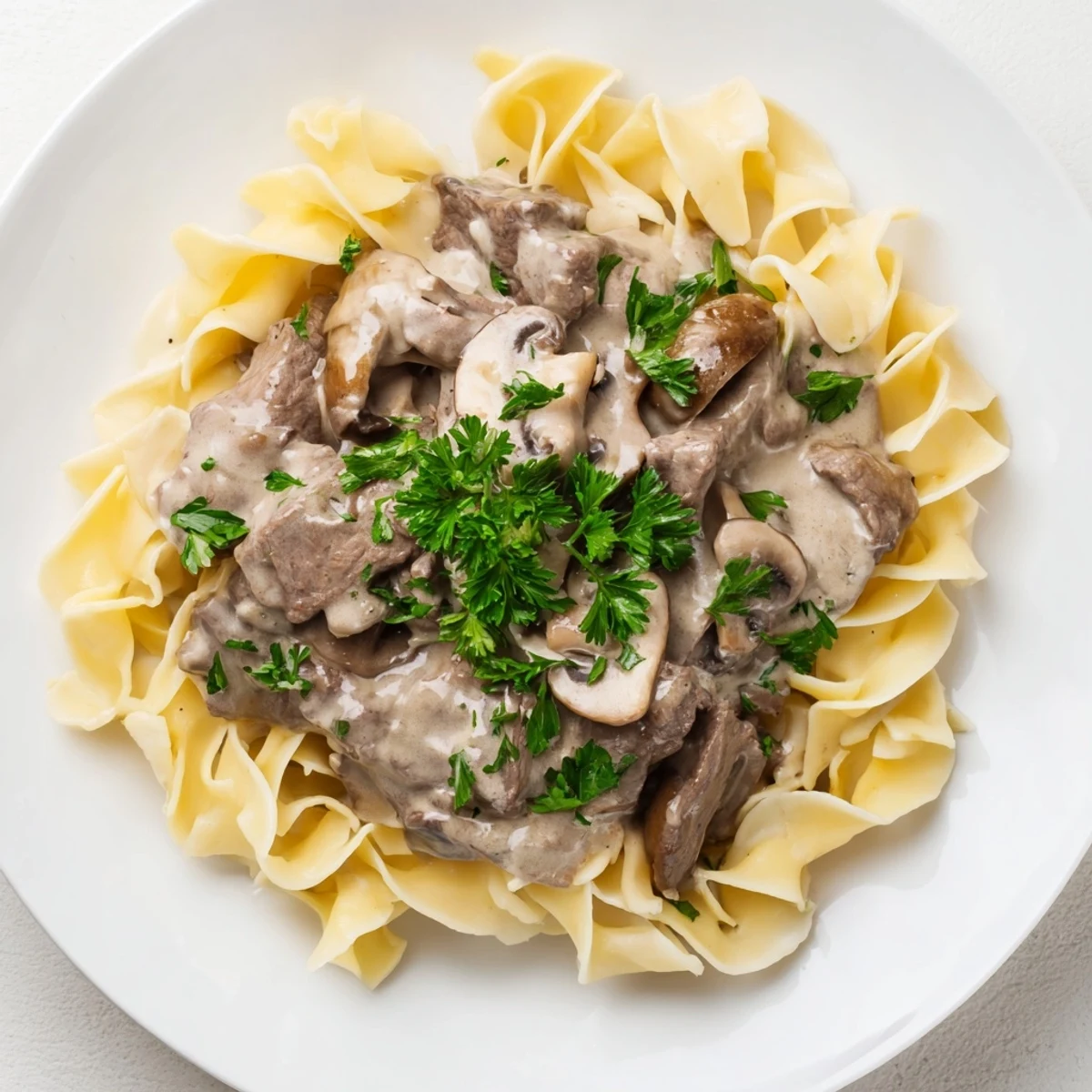 Steaming Beef Stroganoff with Egg Noodles, featuring tender beef strips and creamy mushroom sauce in a rustic skillet.