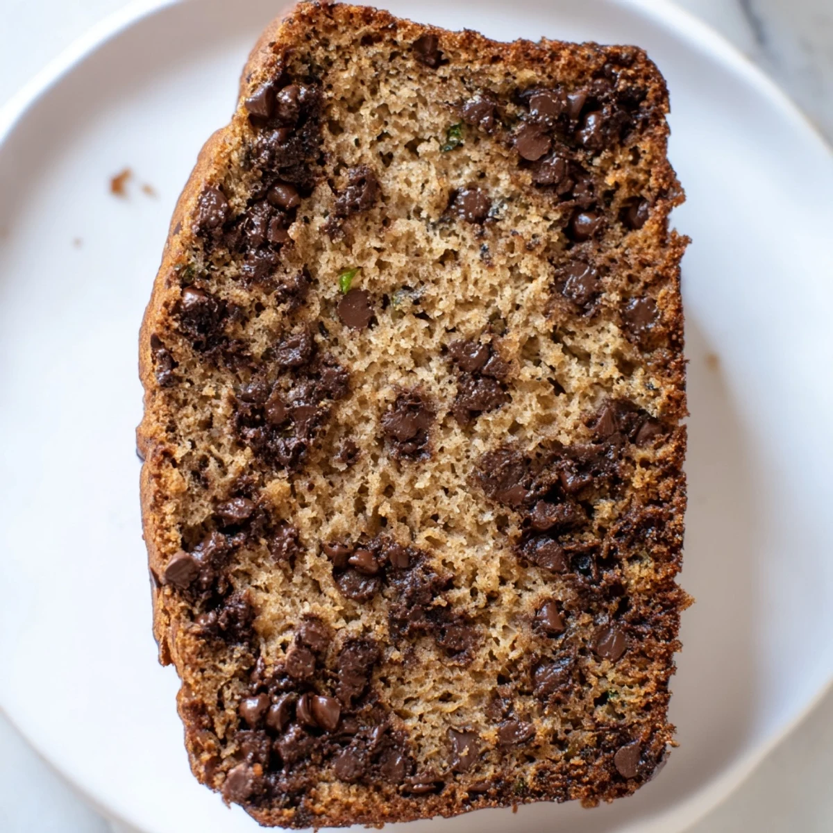 Warm slice of Chocolate Chip Zucchini Bread served on a white plate, ready for breakfast or snacking.