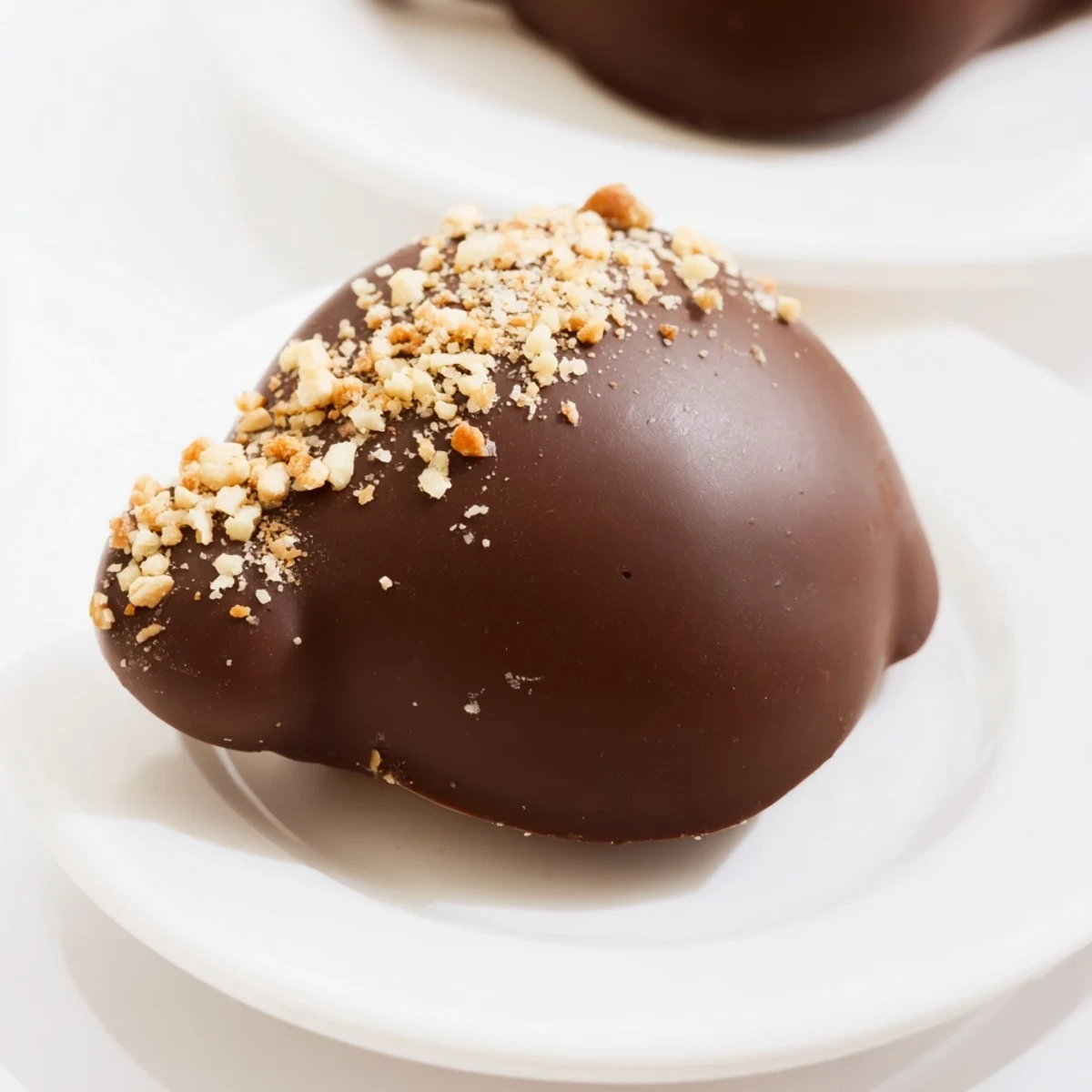 A close-up of Chocolate Covered Marshmallow Peeps with glossy dark chocolate and festive sprinkles on a baking sheet.