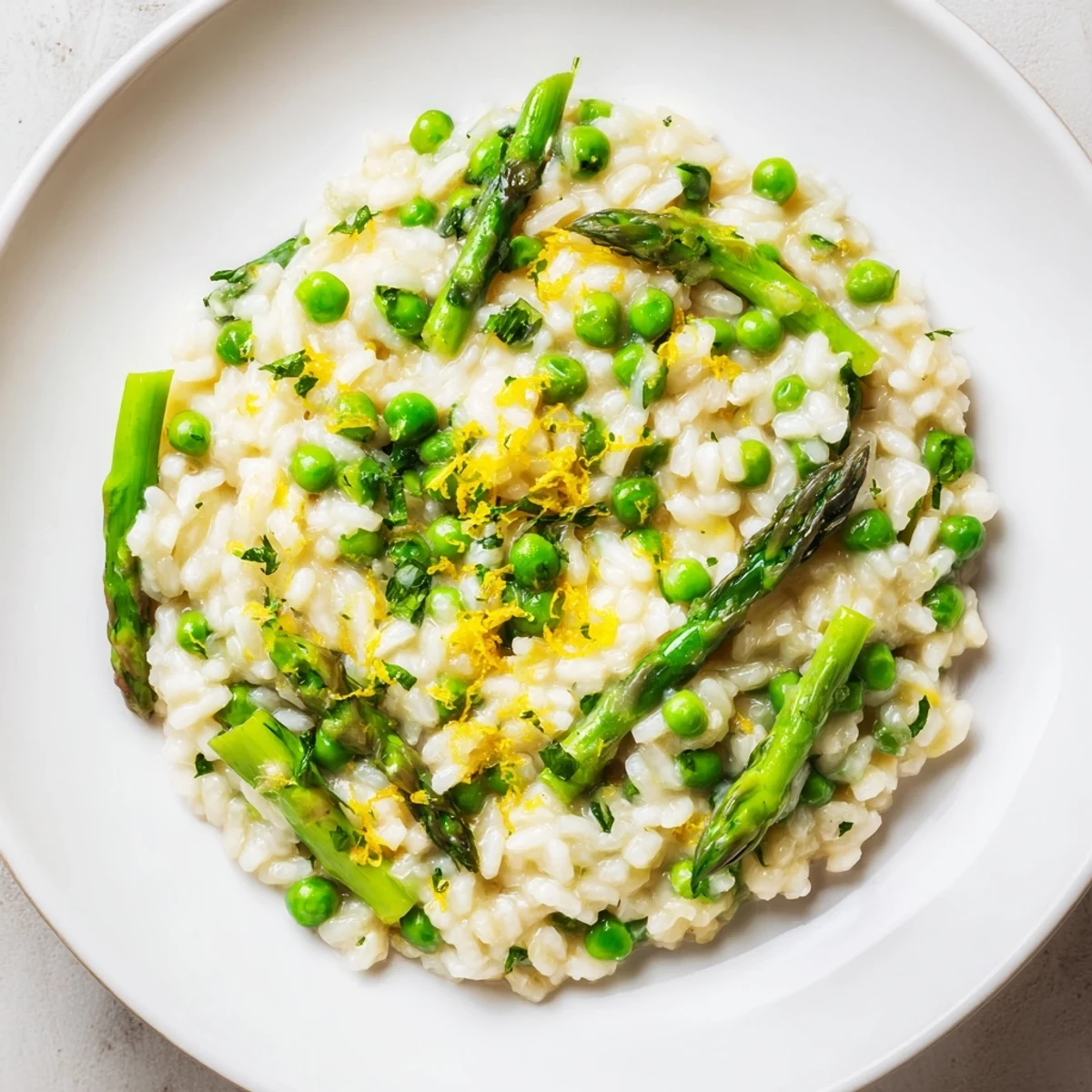 Cremy Spring Pea and Asparagus Risotto in a white bowl, garnished with fresh parsley.