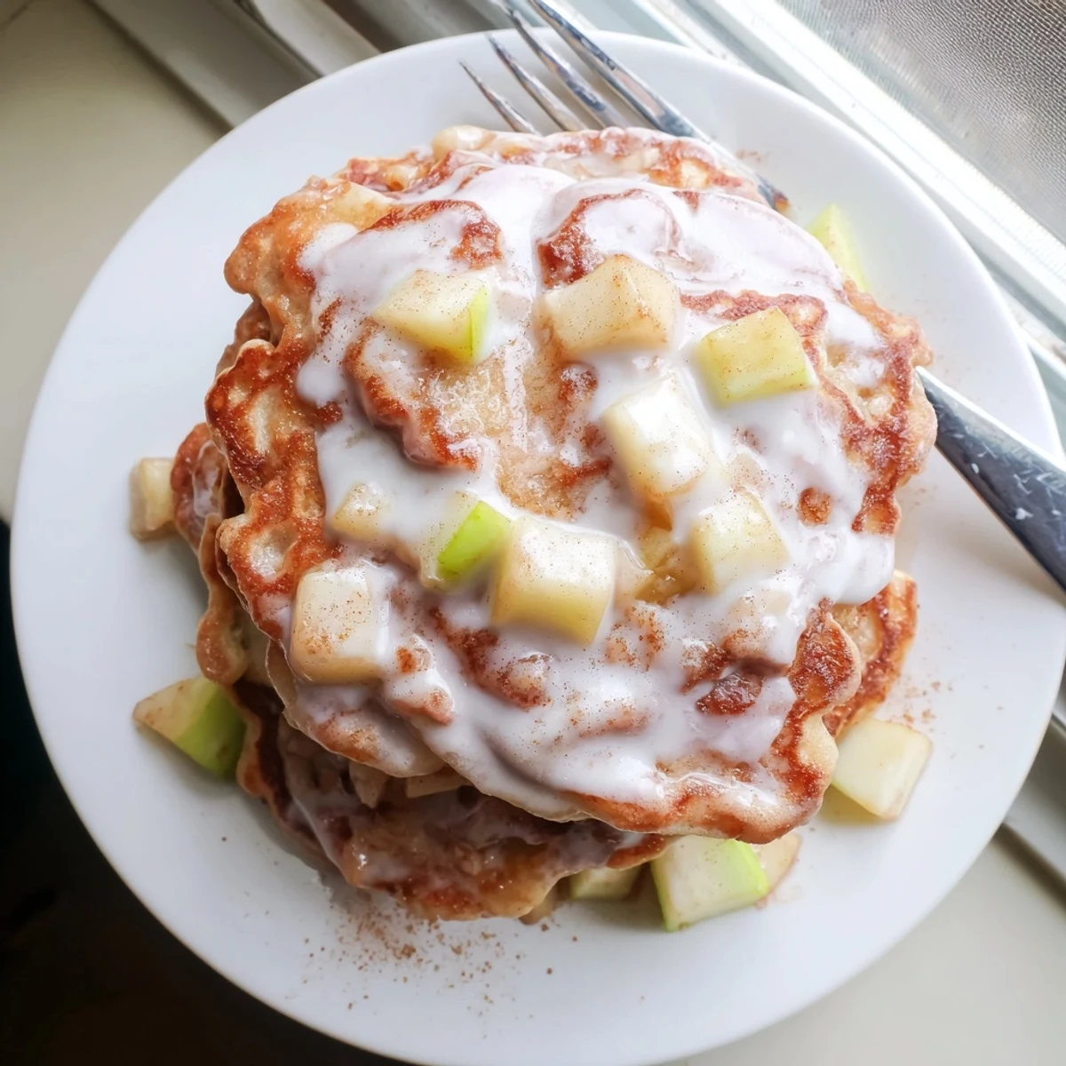 Glazed Apple Fritter Pancakes stack high, drizzled sweetly for a cozy brunch serving idea.