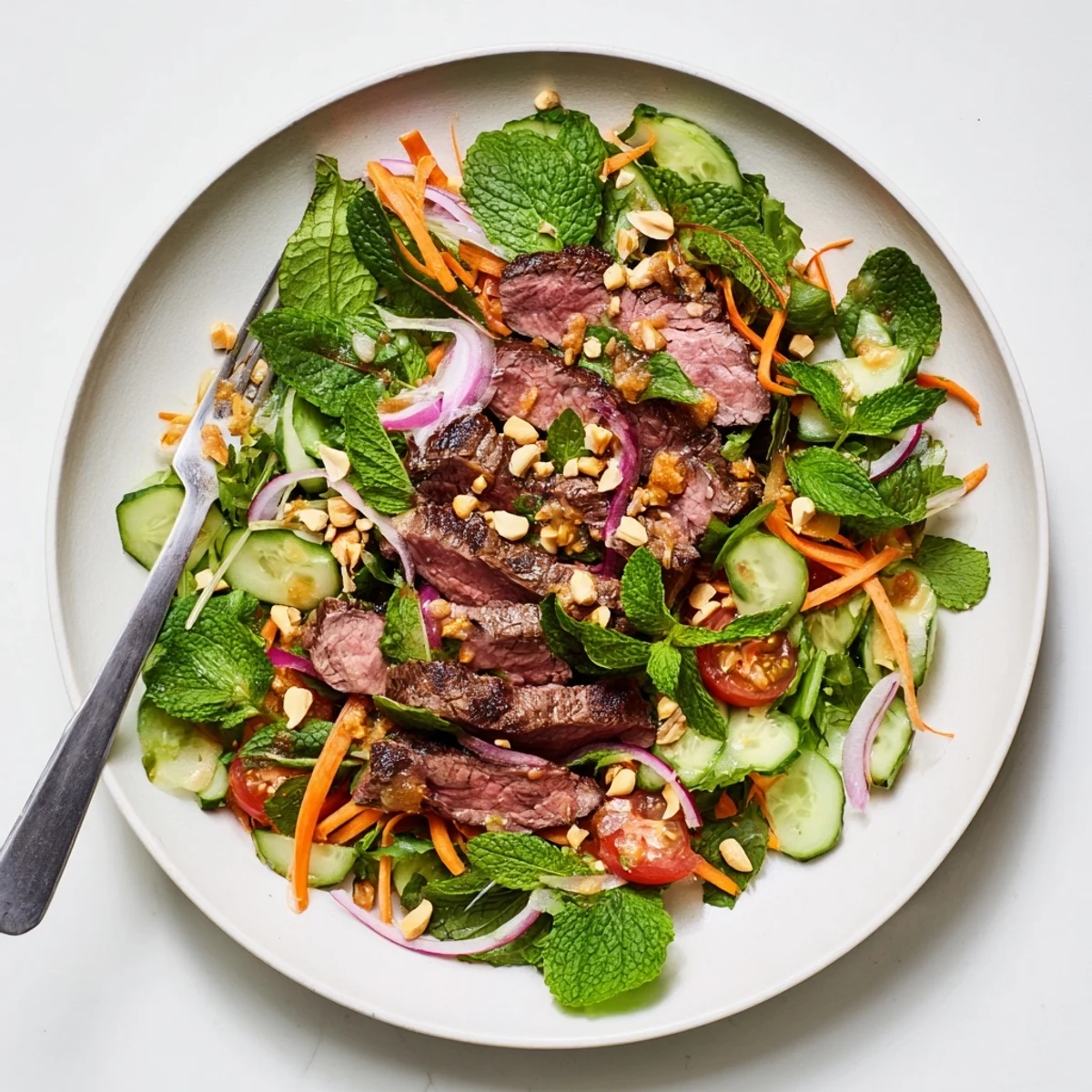 Tender marinated steak meets crunchy cucumbers and peppery greens in this vibrant Vietnamese Beef and Watercress Salad, topped with chopped peanuts and fresh herbs.