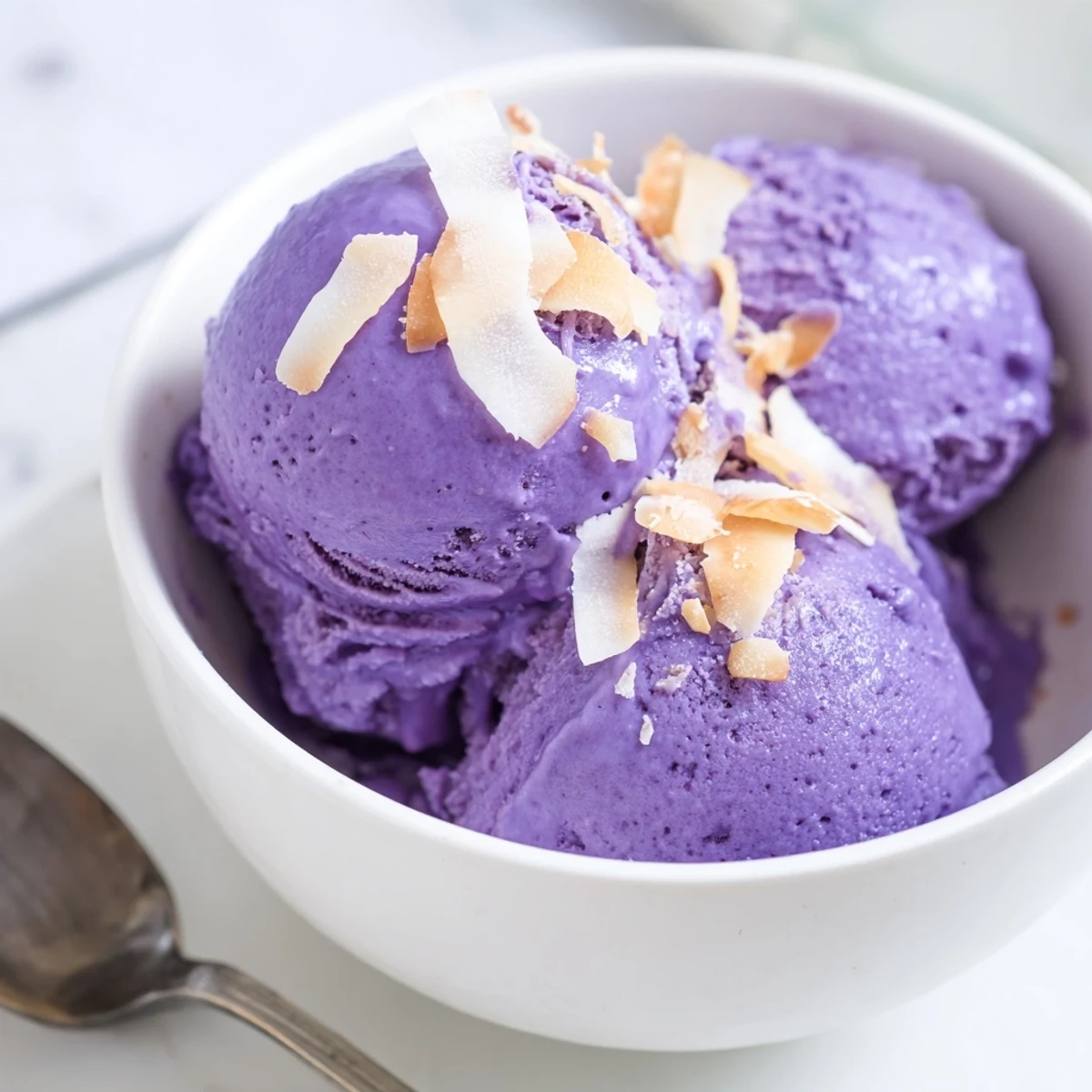 A close-up of homemade Ube Ice Cream in a white bowl, showing its vibrant purple color and creamy texture.
