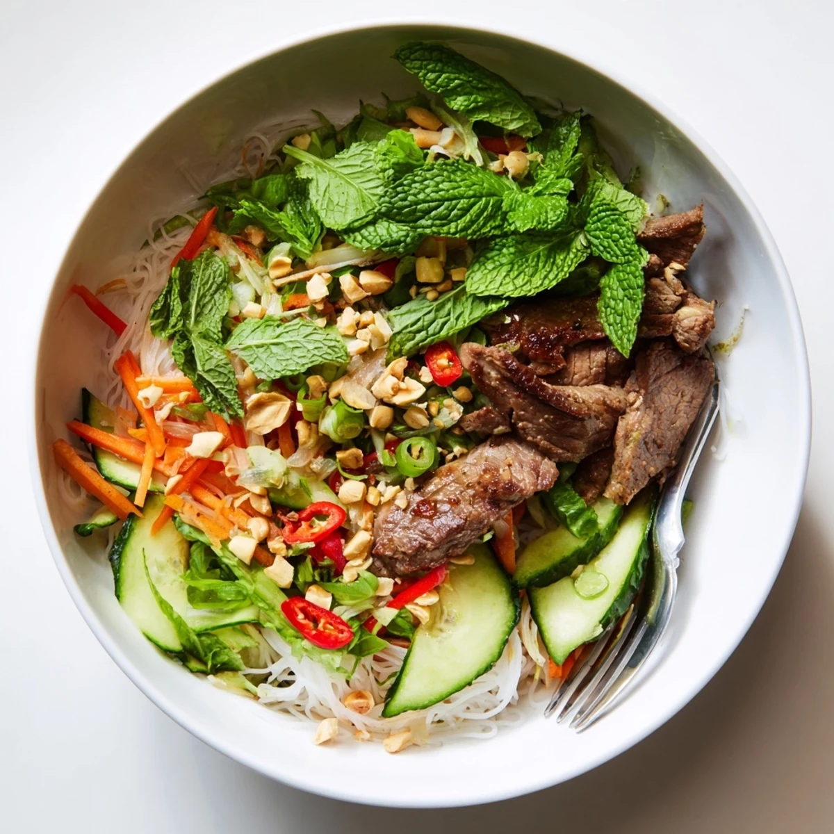 Colorful Bun Bo Xao topped with fresh mint, cilantro, bean sprouts, and sautéed beef.