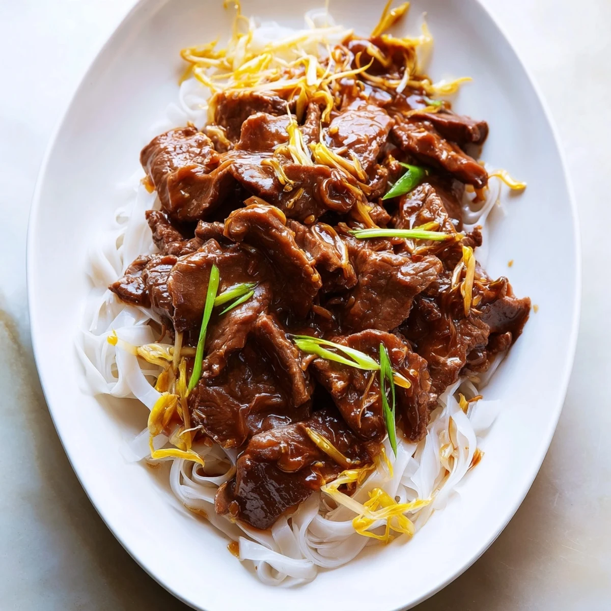 A close-up of Beef Chow Fun with wide rice noodles, seared beef, and fresh bean sprouts on a plate.