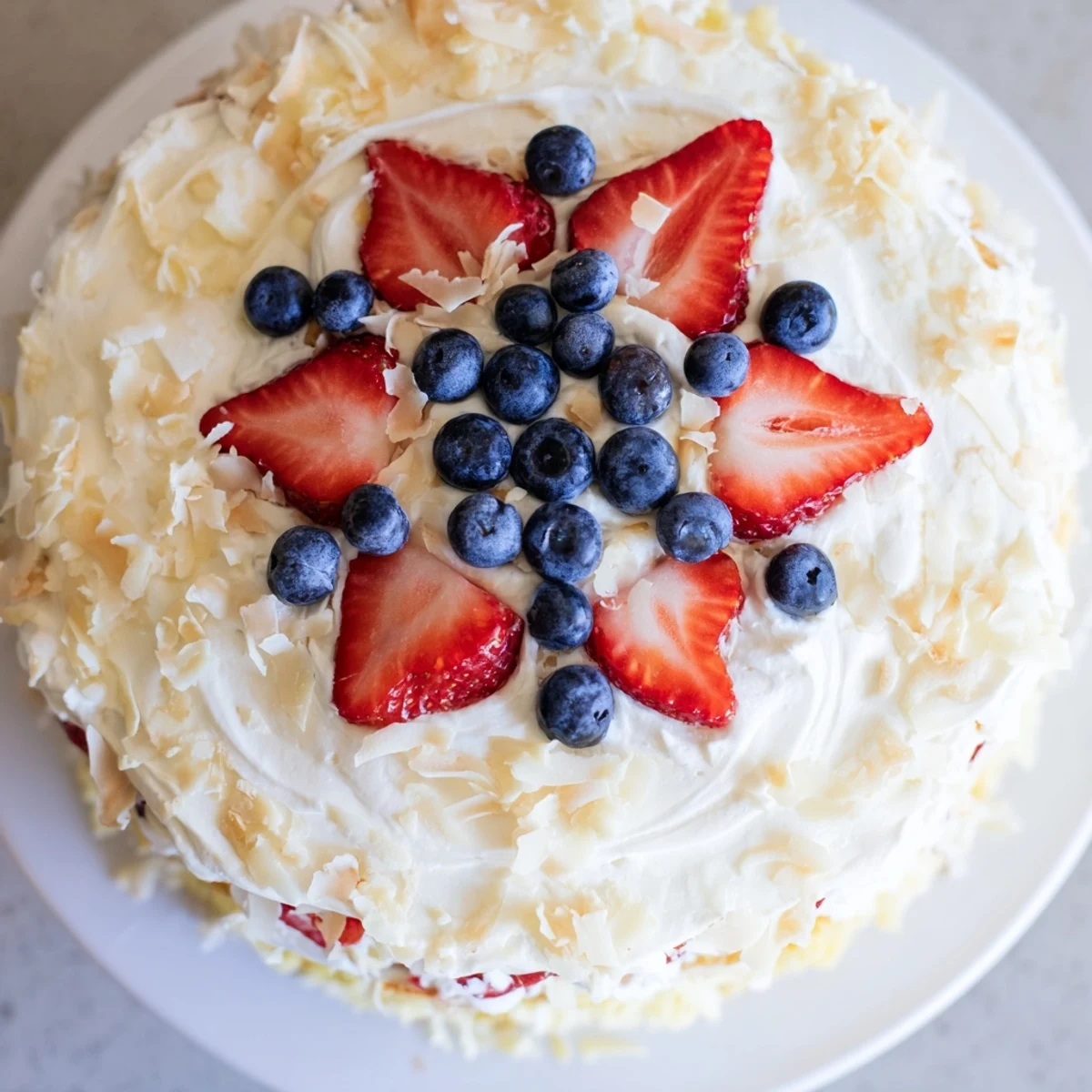 Savory-sweet Pineapple Coconut God Bless America Cake frosted with cream cheese and topped with patriotic berries.