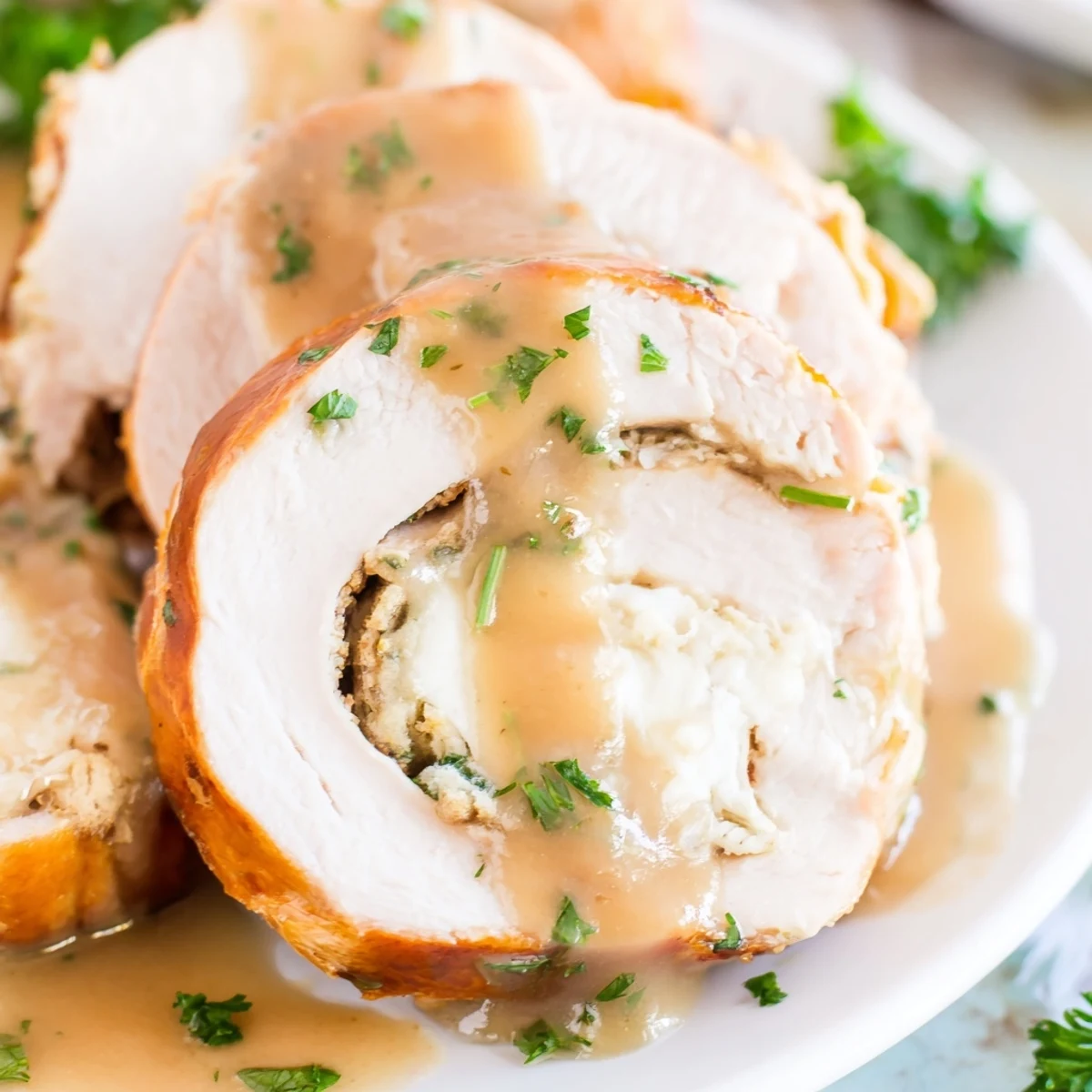 Juicy Flavor-Packed Turkey Roll-Ups with Stuffing served on a plate with gravy drizzled over golden-brown rolls.