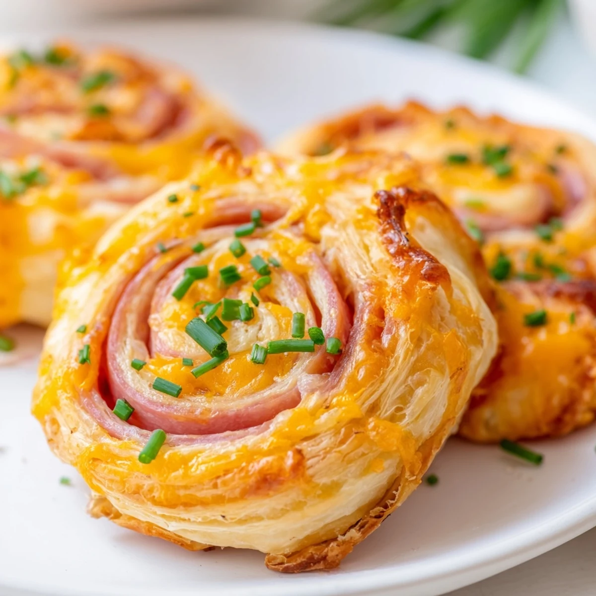 Savory Easter Ham Cheddar Pinwheels showcasing spiral layers of ham, cheese, and herbs on a white plate