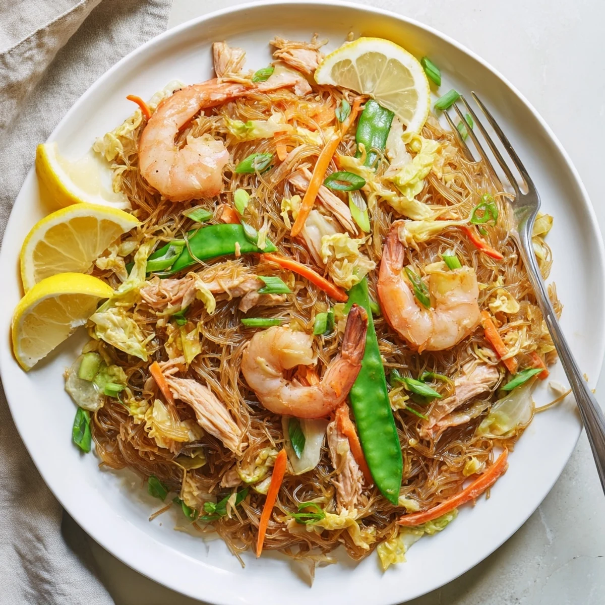 Golden Traditional Pancit Bihon stir-fry with tender rice noodles, chicken, shrimp and colorful vegetables in a savory soy sauce