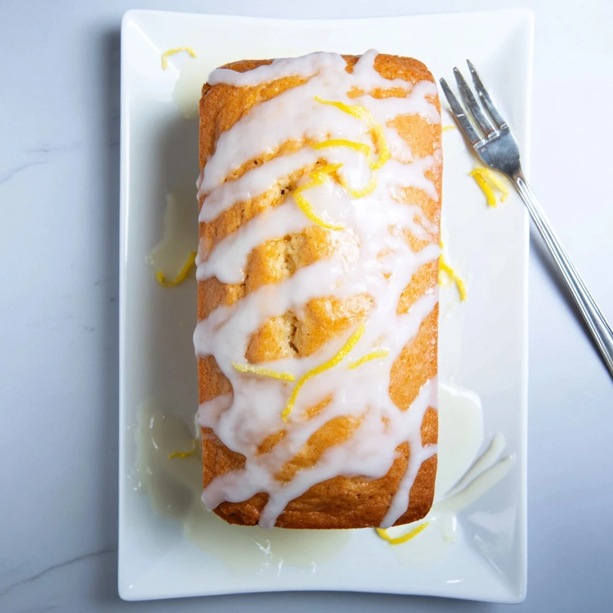 Moist lemon loaf with zesty glaze sliced to reveal tender bright yellow crumb interior