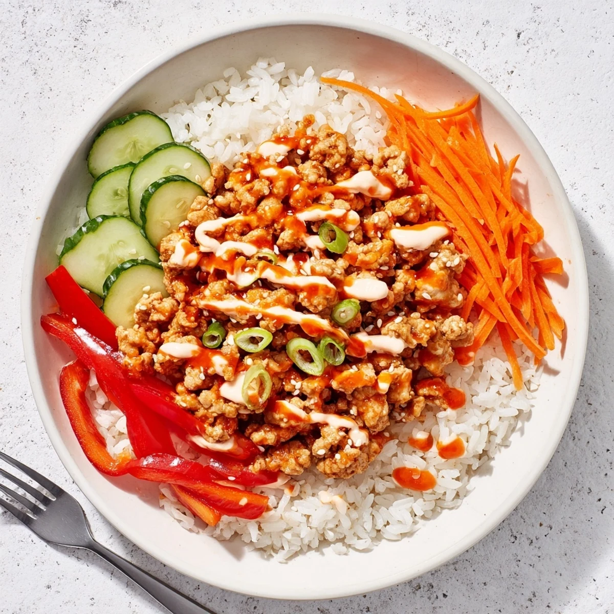 Vibrant firecracker ground chicken bowl served over fluffy jasmine rice with crisp colorful vegetables and creamy sriracha drizzle