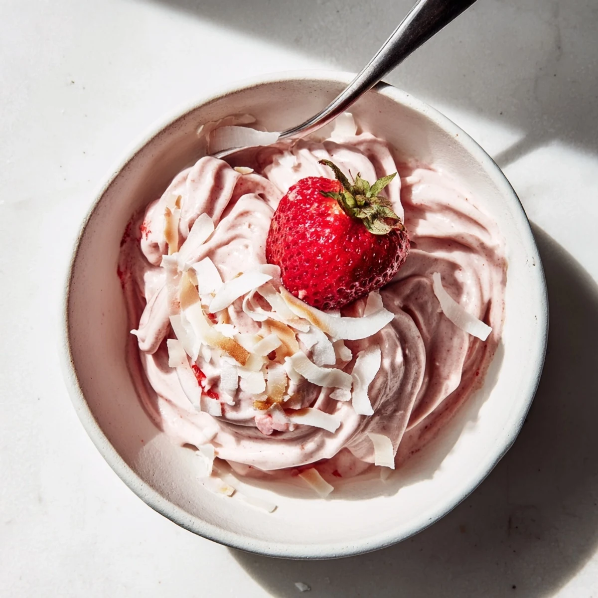 Creamy frozen strawberry Dole Whip delight swirled into a tall glass with fresh strawberry garnish