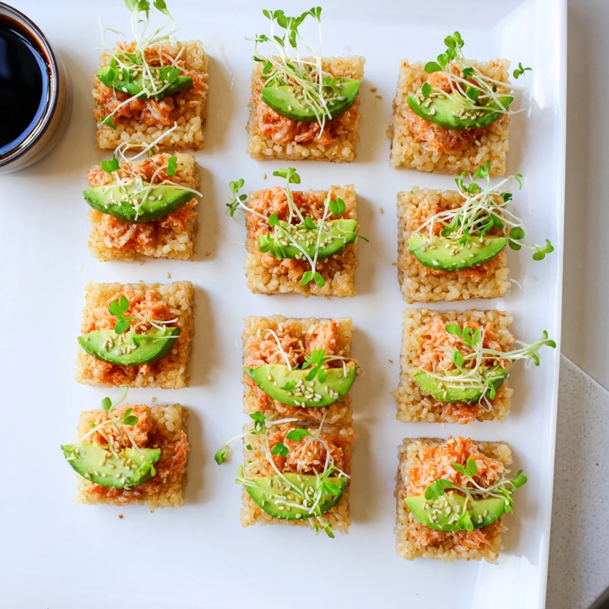 Japanese-inspired salmon crispy rice appetizer garnished with sesame seeds and fresh microgreens