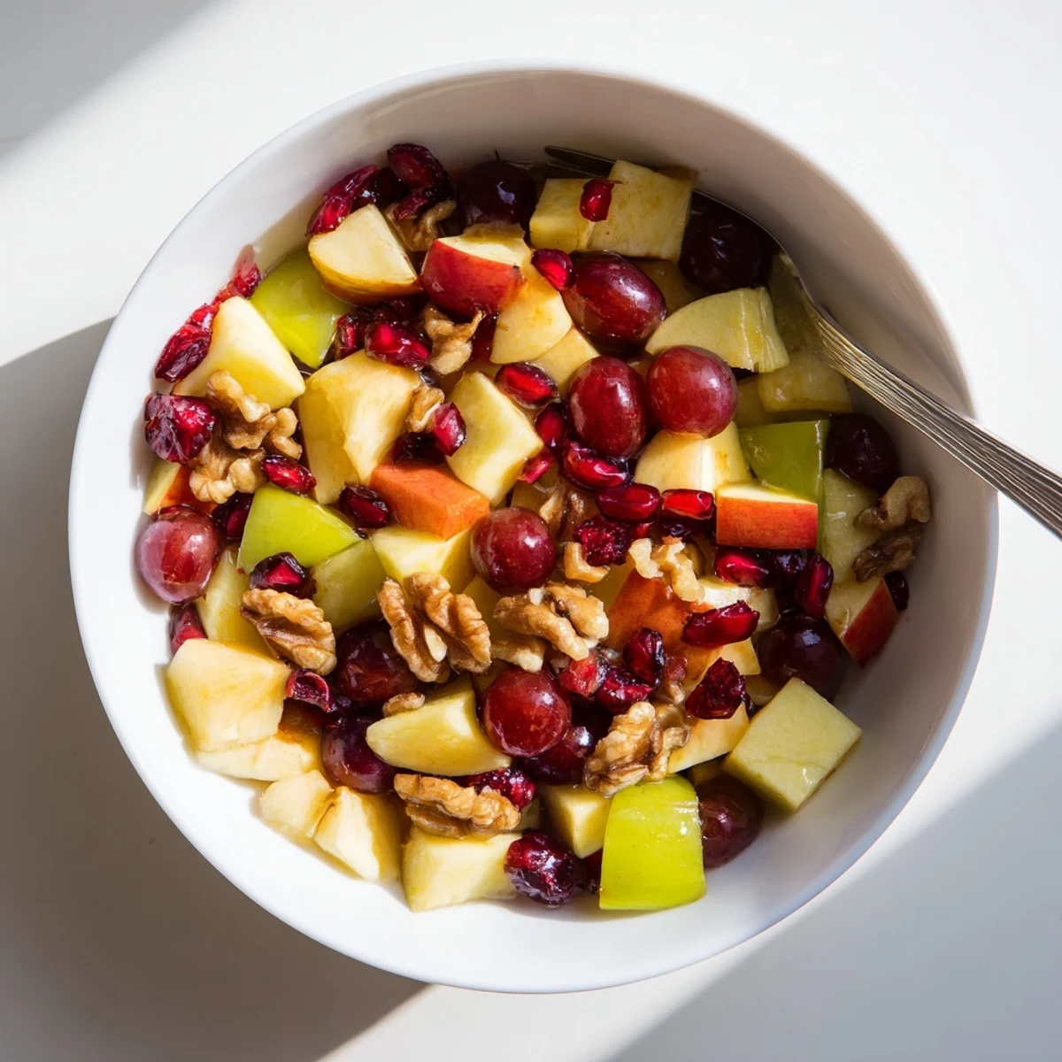 Colorful autumn fruit salad featuring apples pears pomegranate and dried cranberries in honey glaze