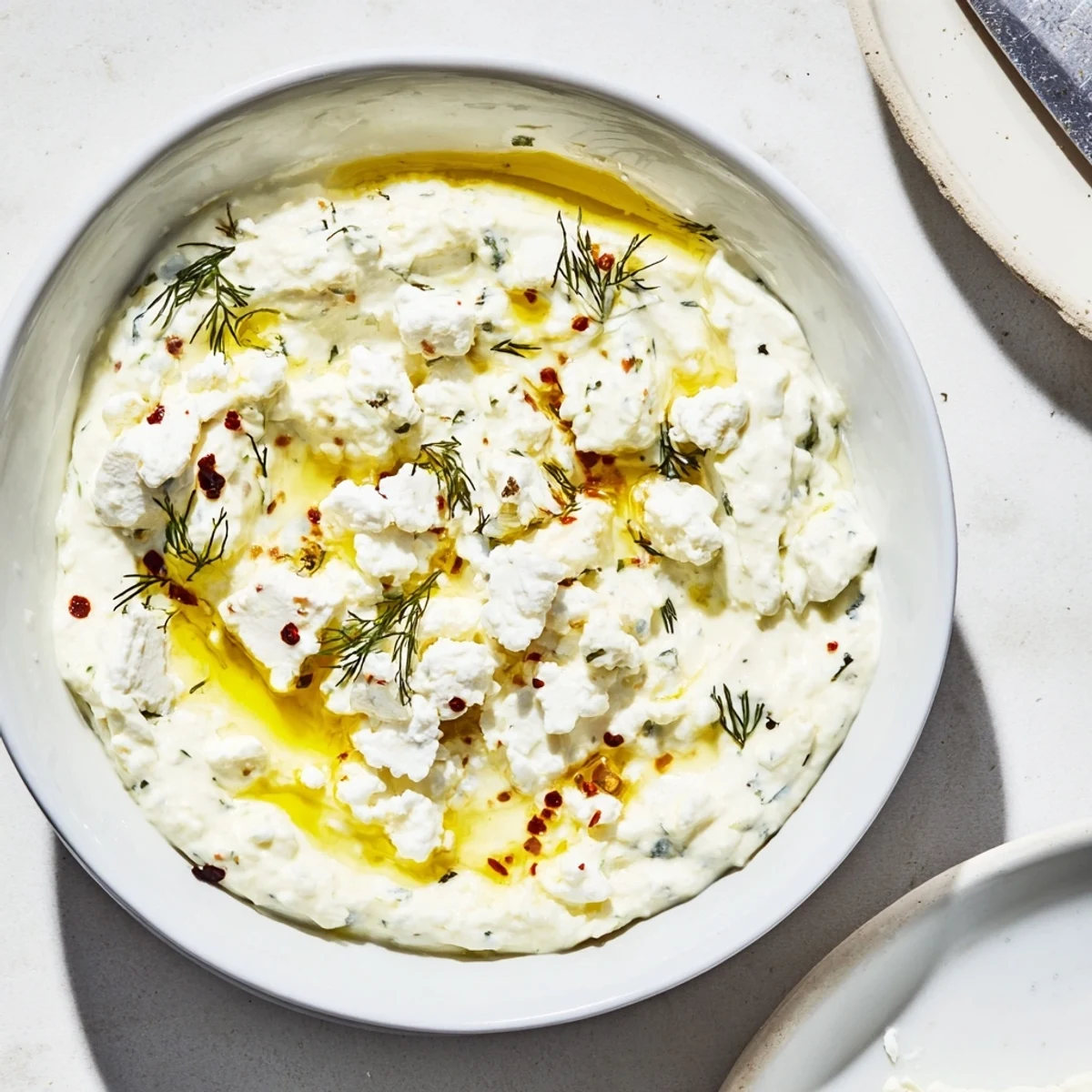 Creamy classic feta dip topped with olive oil and fresh herbs in a serving bowl