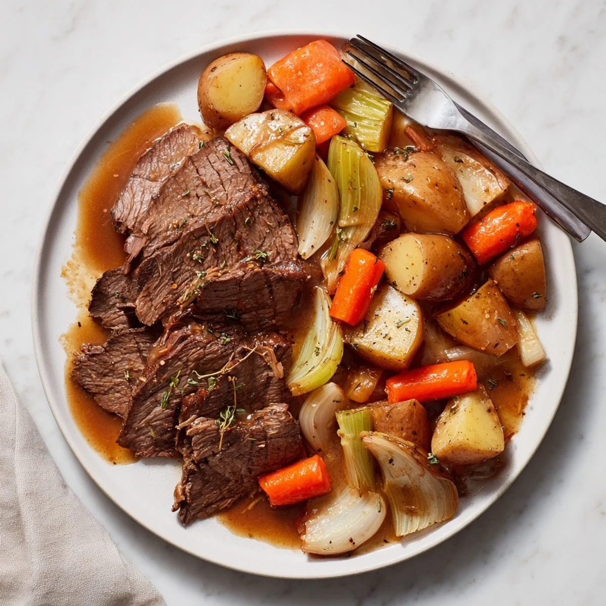 Sliced Southern style pot roast arranged with roasted potatoes and carrots under a glossy homemade gravy coating