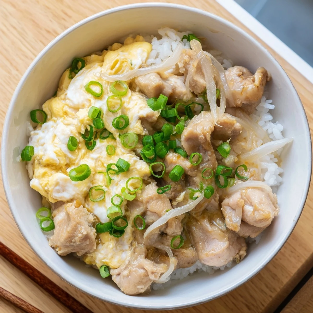 Golden Oyakodon bowl featuring tender chicken and fluffy eggs over steaming white rice