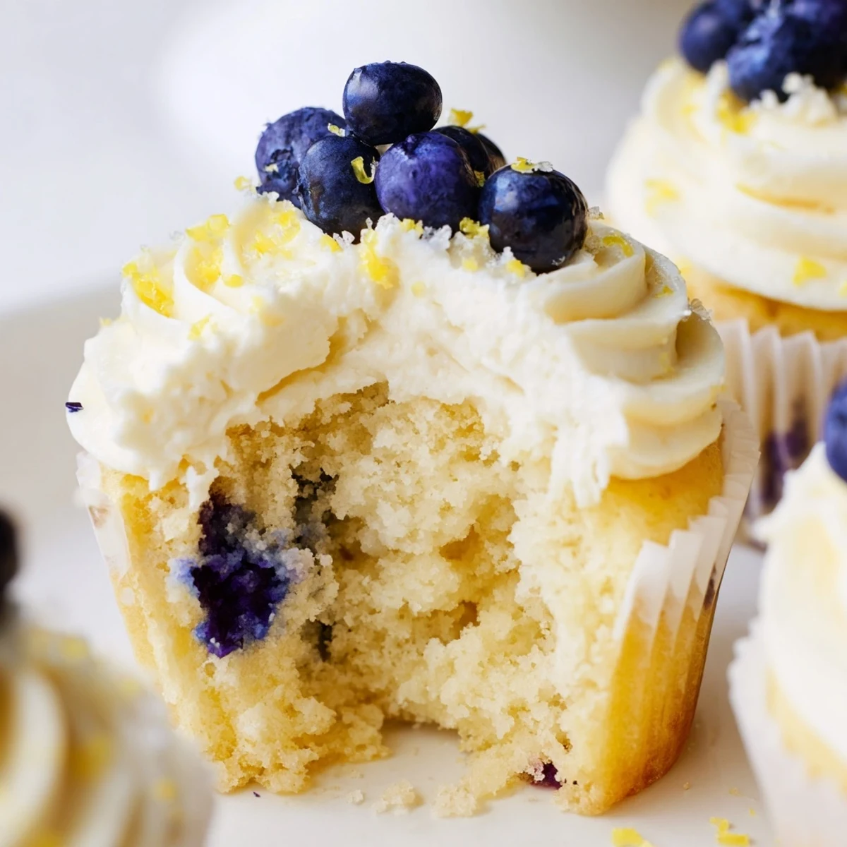 Fluffy lemon blueberry cupcakes topped with tangy cream cheese frosting and fresh berries