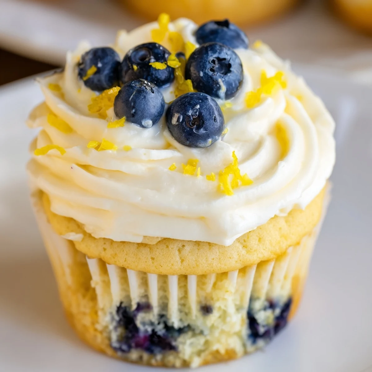 Golden baked cupcakes studded with juicy blueberries beneath swirled lemon cream cheese frosting