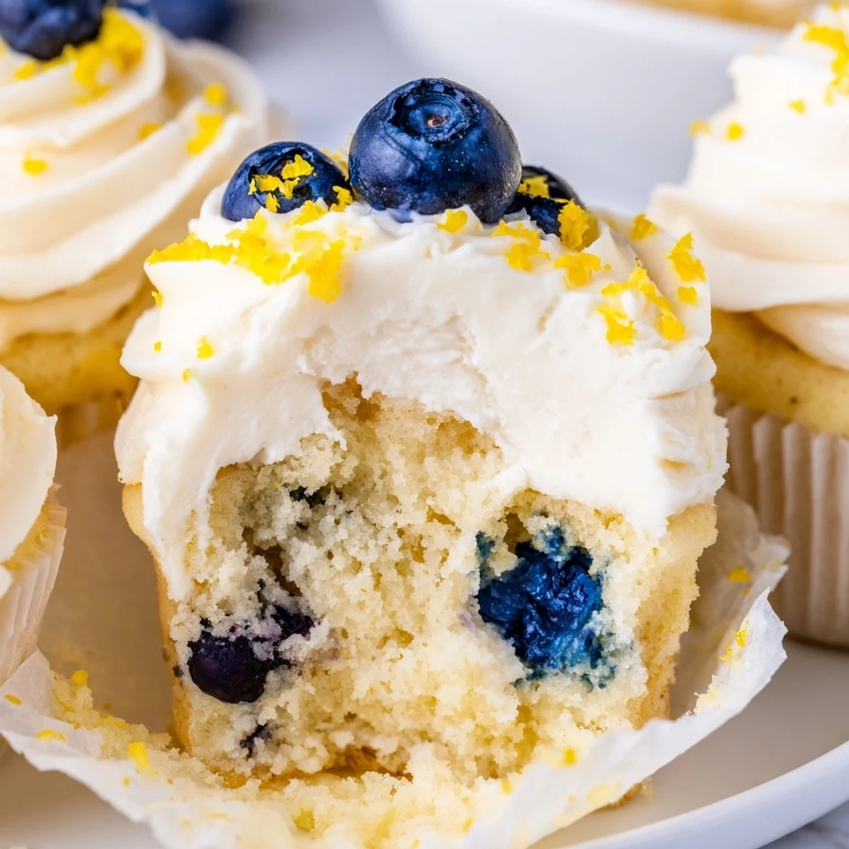 Light and zesty lemon blueberry cupcakes with creamy frosting on a white plate