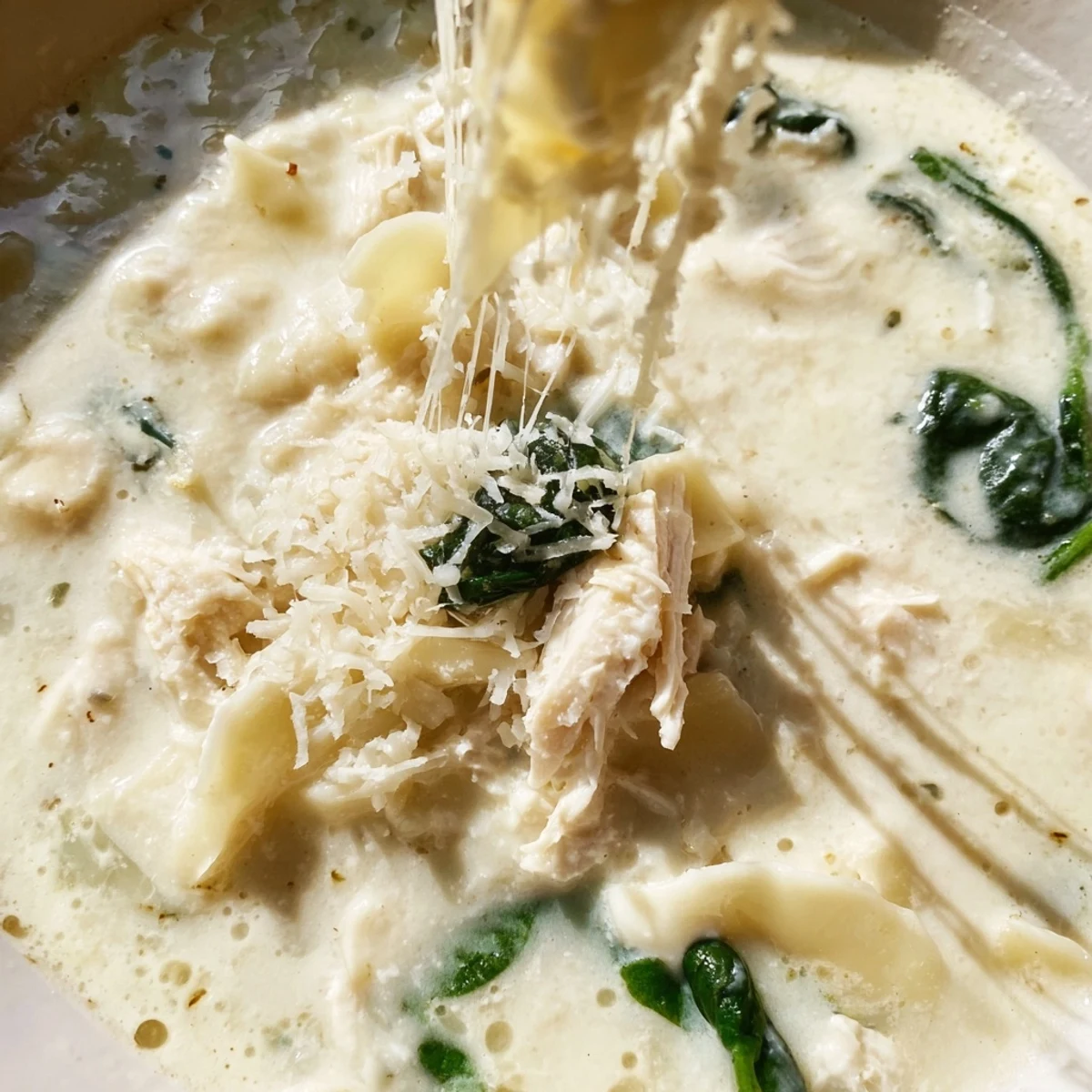 Creamy white lasagna soup with tender noodles and melted mozzarella in a white bowl