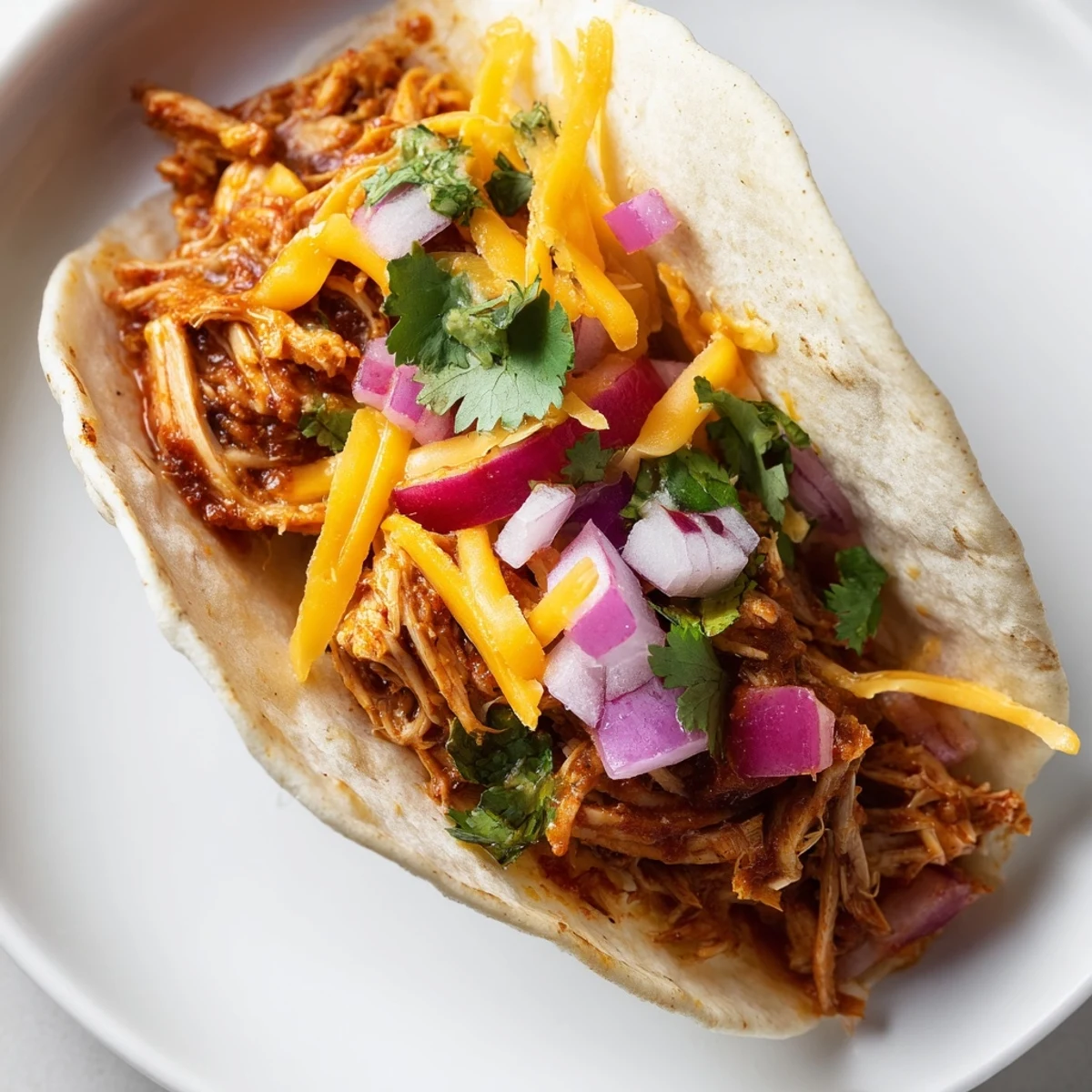 Tender seasoned chicken spilling from crispy taco shells topped with bright diced tomatoes and cilantro