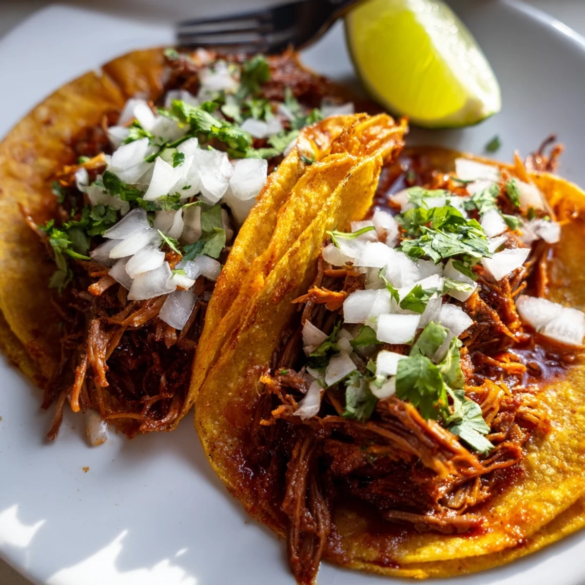 Shredded beef slow cooker birria tacos drizzled with rich red chile broth