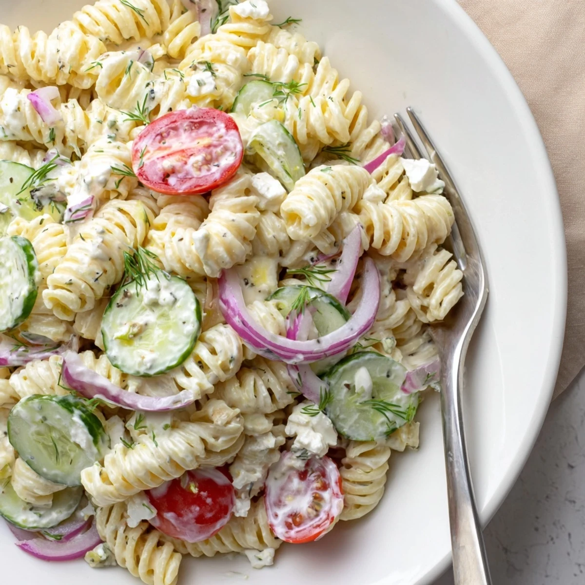 Glistening bowl of Cucumber Pasta Salad with creamy yogurt dressing, dill.