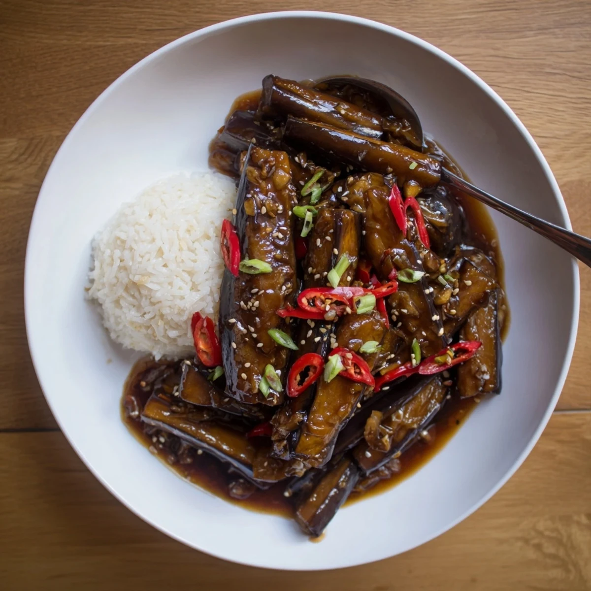 Warm Sichuan Style Braised Aubergines served over steamed jasmine rice, aromatic and tender.
