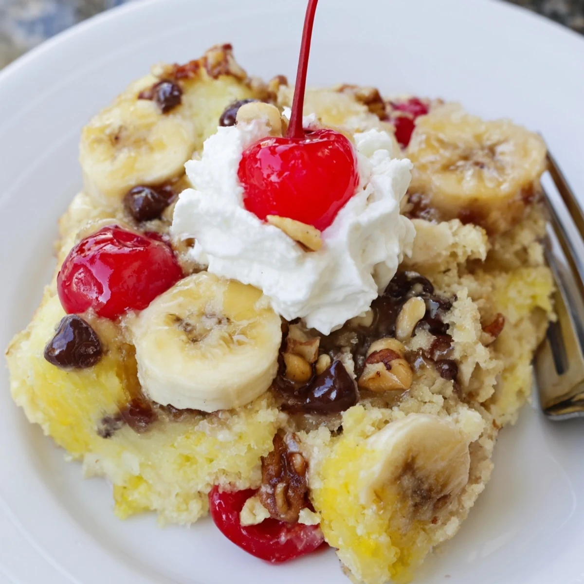 Hot Banana Split Dump Cake bubbling with melted chocolate, cherries, and whipped cream