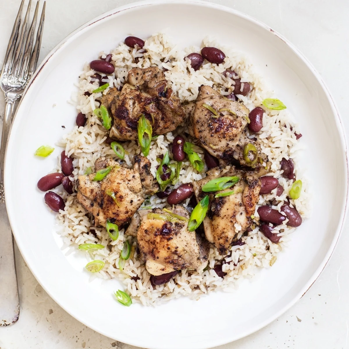 Golden jerk-marinated chicken thighs served over fluffy coconut rice with red kidney beans