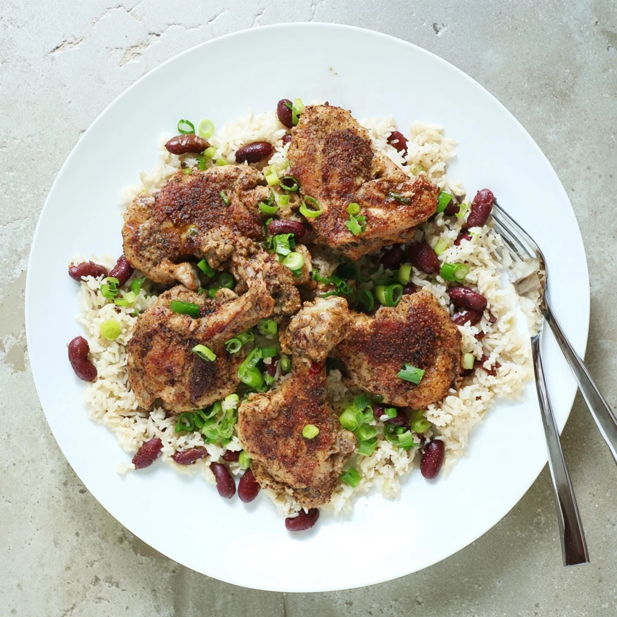 Succulent jerk roasted chicken resting on creamy coconut kidney bean rice with green onions