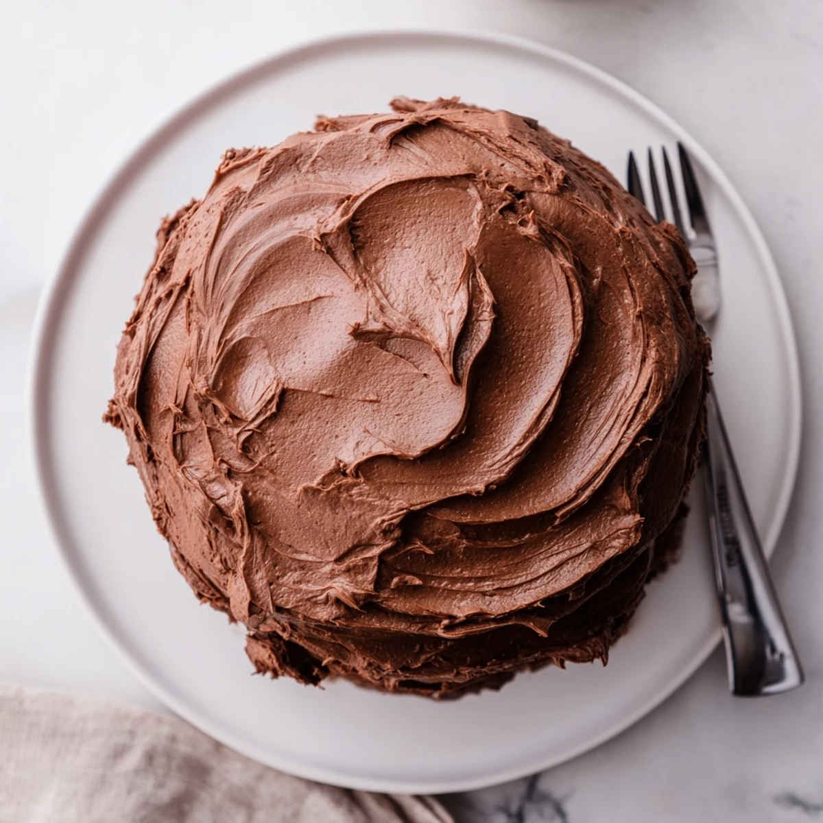 Slice of Matilda chocolate cake revealing tender crumb topped with creamy chocolate buttercream frosting.