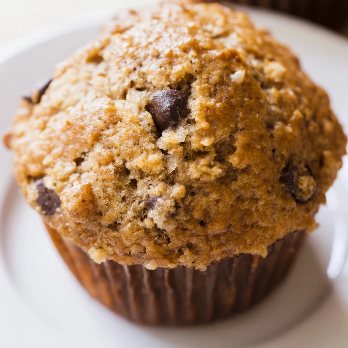 Golden peanut butter banana muffins topped with melty chocolate chips on a white wire cooling rack