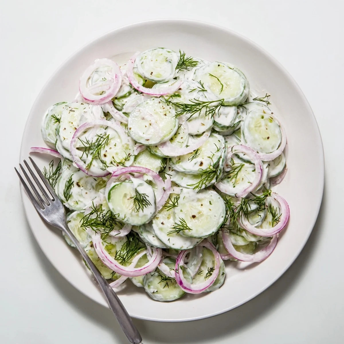 Light and refreshing cucumber dill salad topped with fresh dill in a glass bowl for outdoor dining