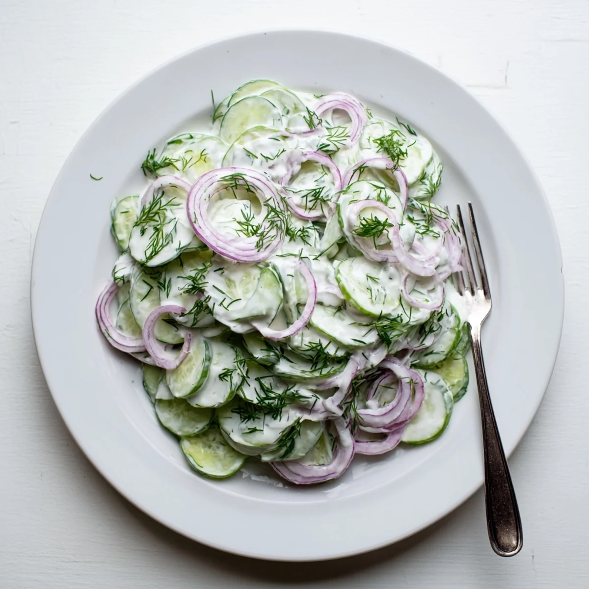 Crisp cucumber dill salad featuring tangy sour cream dressing and thinly sliced vegetables on a summer table