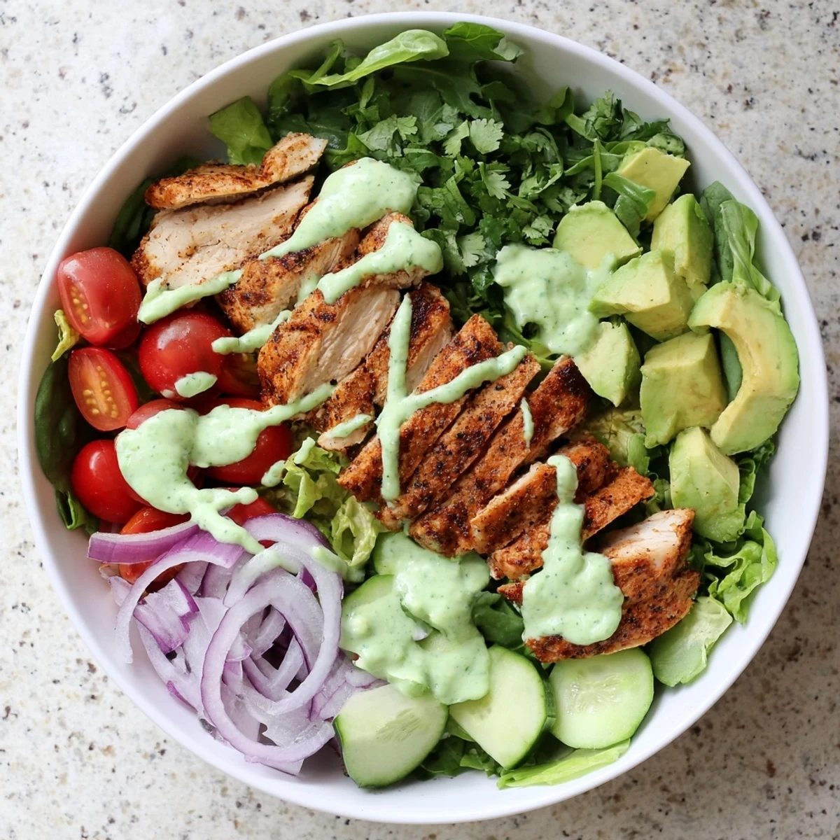 Juicy sliced grilled chicken rests on mixed greens with ripe avocado chunks and crisp colorful vegetables in a healthy bowl arrangement