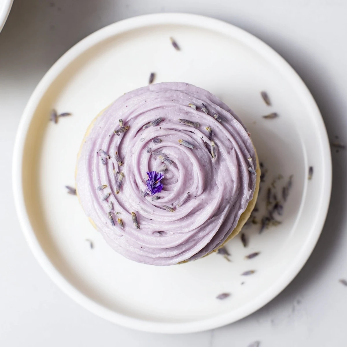Pale purple Lavender Buttercream Floral Frosting topped with edible violets, creamy texture.