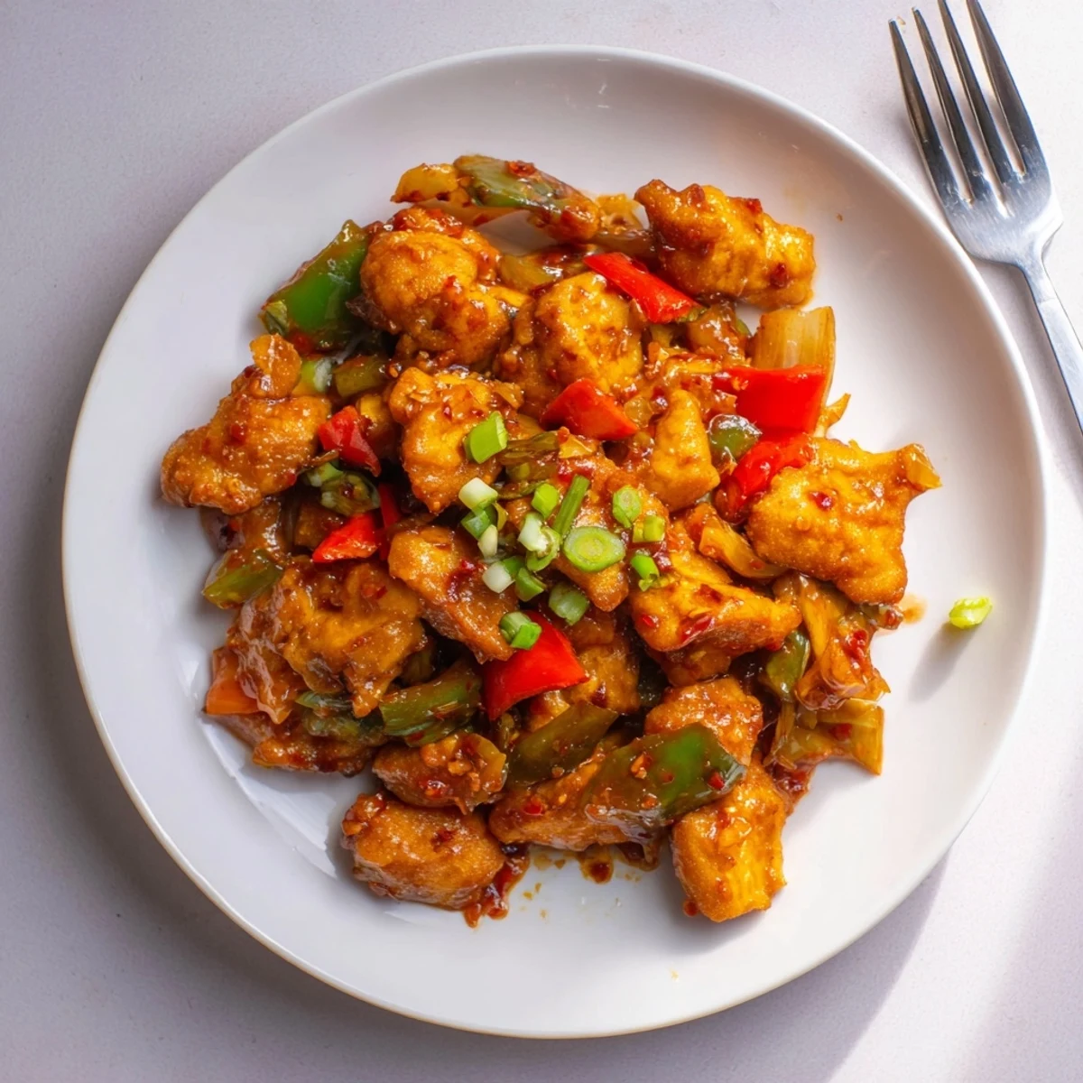 Plate of Flavorful Chilli Chicken Indo Chinese garnished with spring onions, steaming