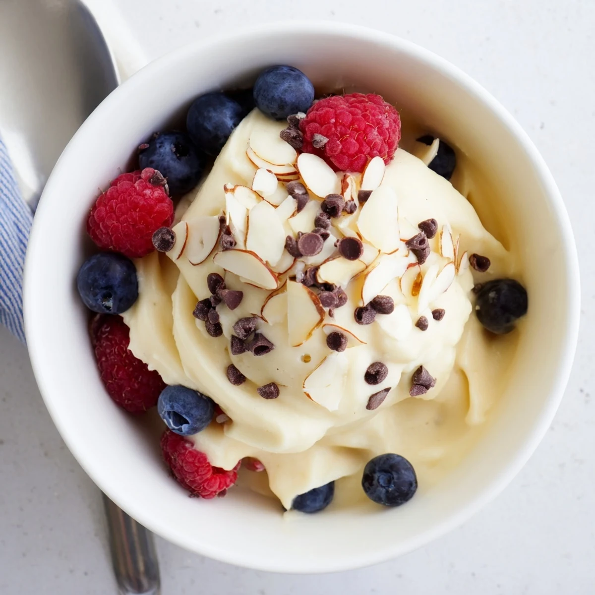Creamy banana nice cream served in bowls topped with fresh berries and dark chocolate chips