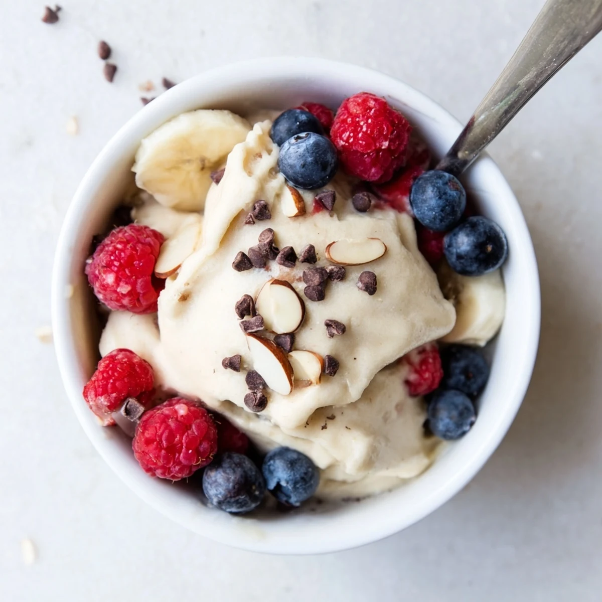 Vegan banana nice cream recipe displaying thick soft-serve texture with chopped nut toppings