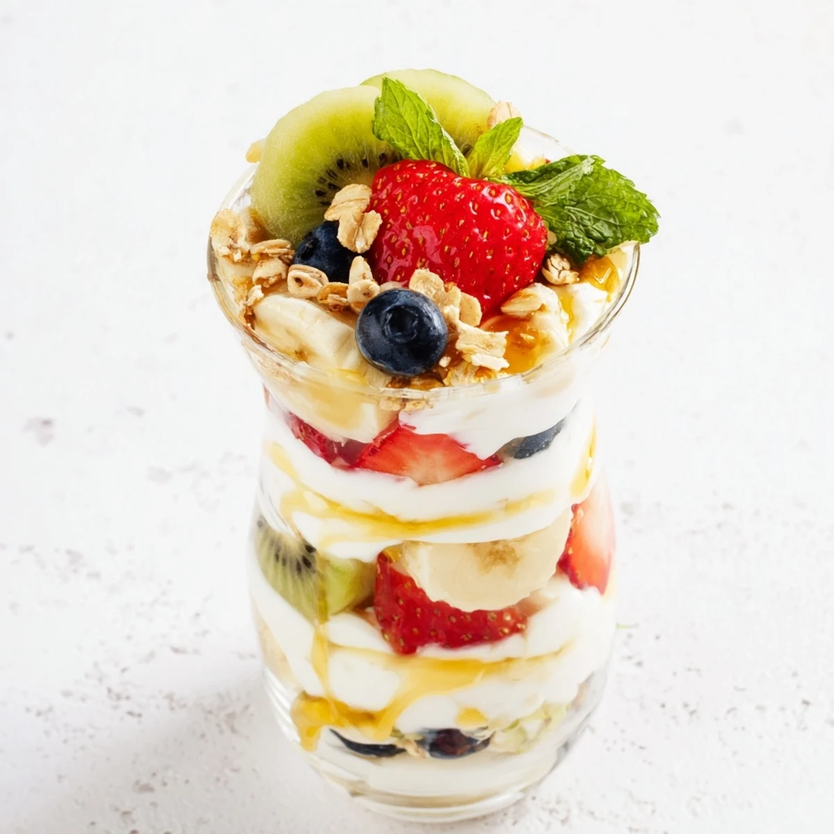 Layered yogurt parfait recipe with honey drizzle and colorful fresh fruits in clear glass