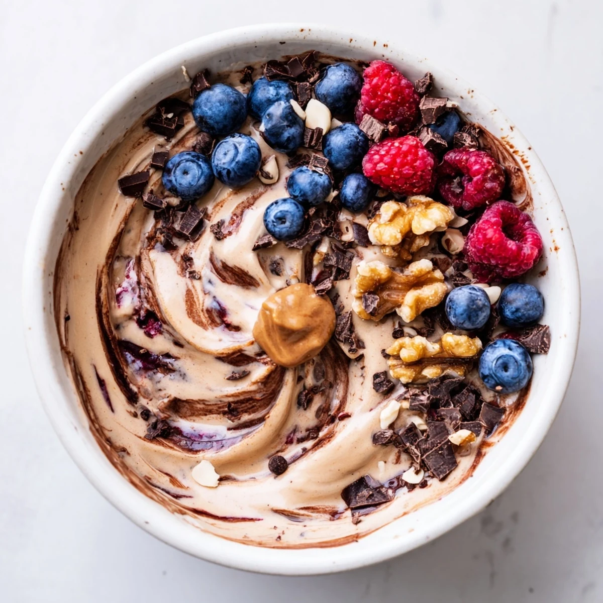 Creamy healthy nice cream recipe topped with fresh berries and dark chocolate shavings in a bowl