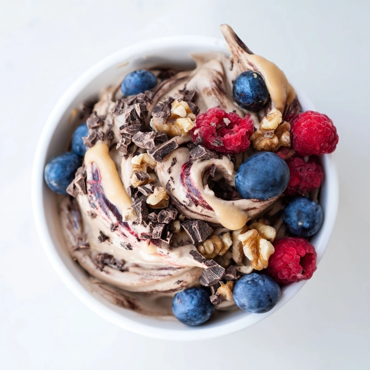 Vegan healthy nice cream recipe served soft-serve style with banana slices and chopped nuts