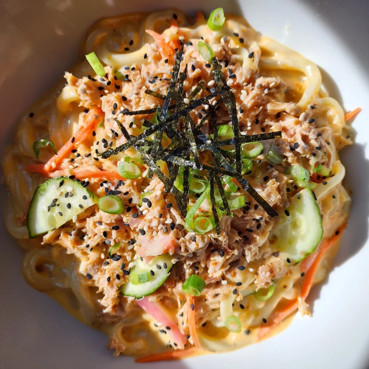 Glossy udon noodles tossed with spicy tuna in a rich sesame Sriracha sauce