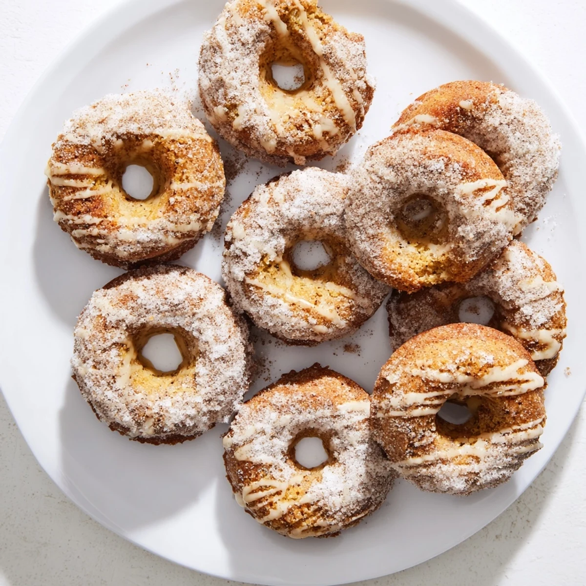 Moist banana bread donuts with sweet glaze drizzle served on a white plate