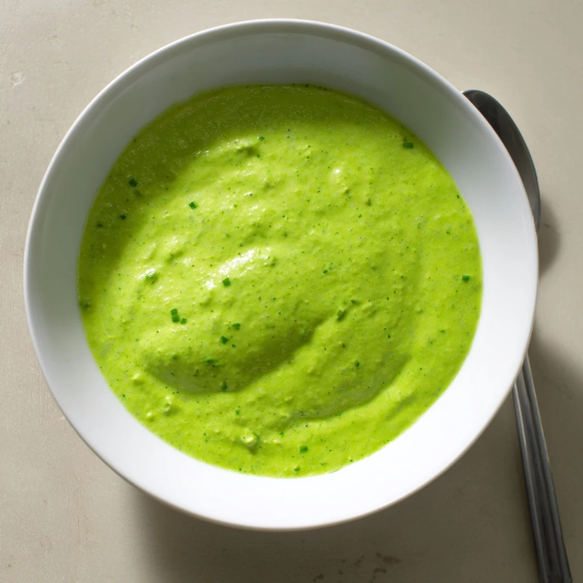 Vibrant bowl of spicy aji verde Peruvian green sauce served with crispy vegetable sticks